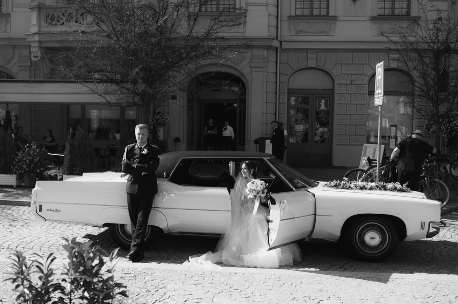 Uśmiechnięta para młoda wychodząca z retro auta do ślubu Oldsmobile Ninety-Eight