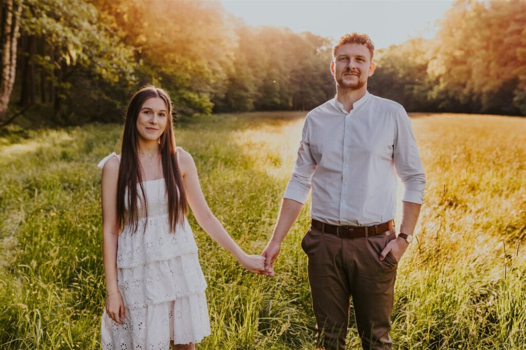 młoda para stojąca na tle zachodzącego słońca w polu – wynajem auta do ślubu